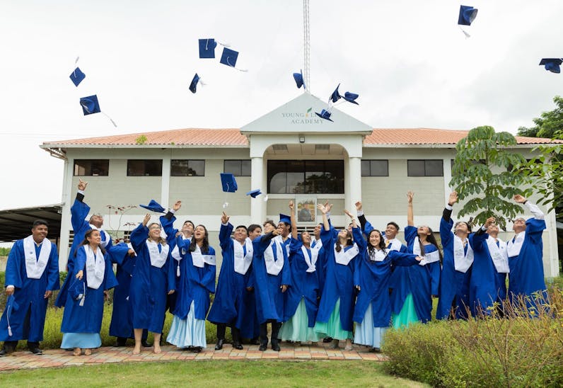 Graduates in Ecuador toss their graduation caps in the air outside of the Young Living Academy.