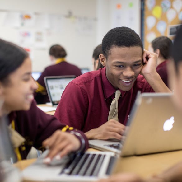  Senior male and female students smile while working on assignments on laptops 
