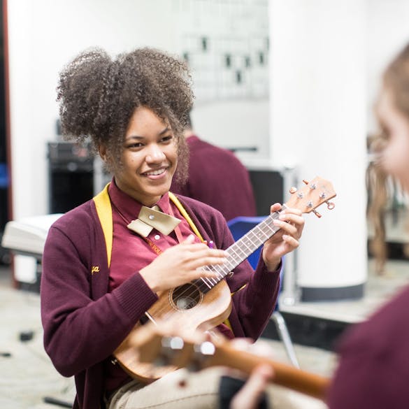  Two young female students play stringed instruments in music class 