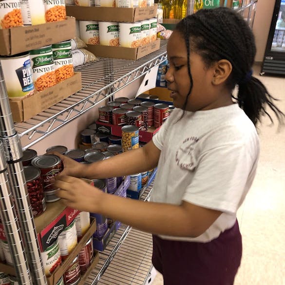 Young female student stacks canned foods on a shelf 