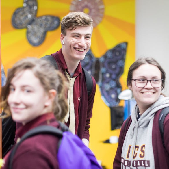  High school students laughing in school hallway 