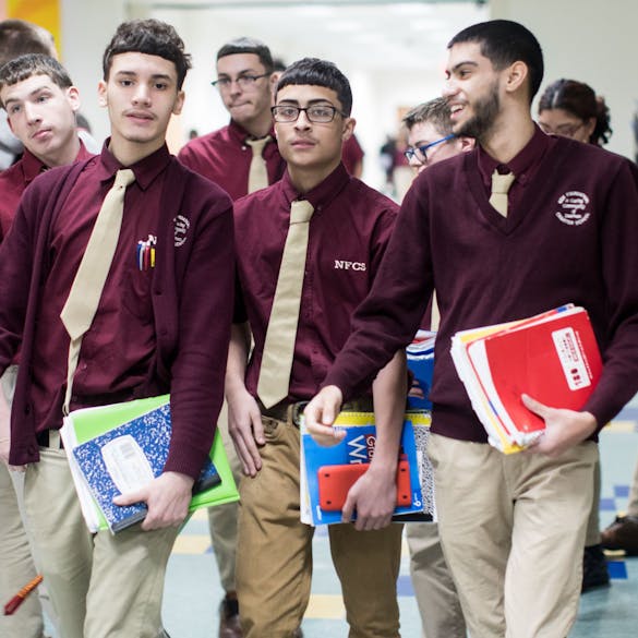  Several male high school students walking down the school hallway. 