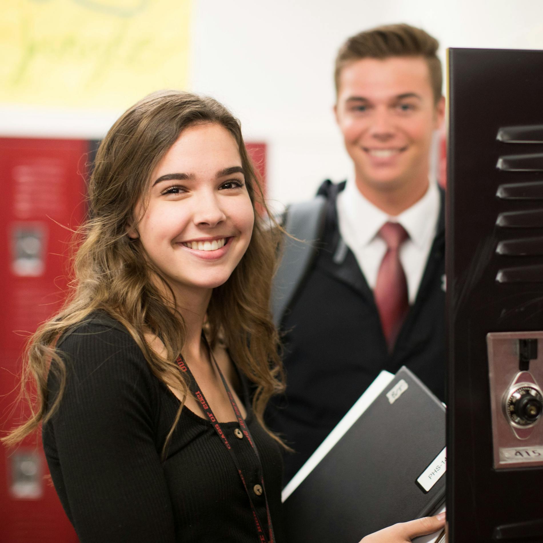 A female and a male student smiling by lockers.