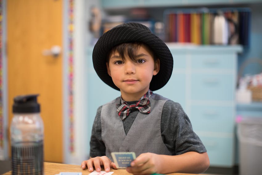 Boy wearing hat working with cards at desk.