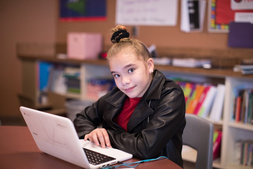 Female student working on Chromebook at table.